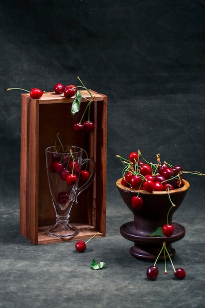 Stilleven met rijpe rode kersen met een vaas en een glas