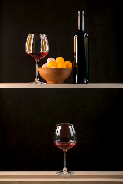 Stilleven met veelkleurige ballen in een bord een fles en glazen wijn