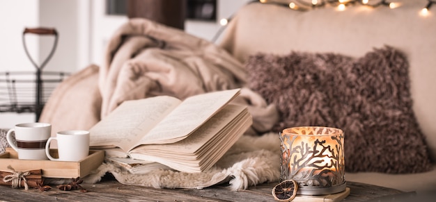 stilleven thuis sfeer in het interieur met bekers, een boek en kaarsen, op de muur van gezellige spreien