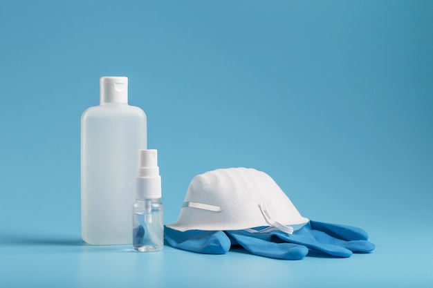 Stilleven van antivirusbescherming op een blauwe achtergrond, masker, rubberen handschoenen, een fles handdesinfecterend middel, antiseptische gel.