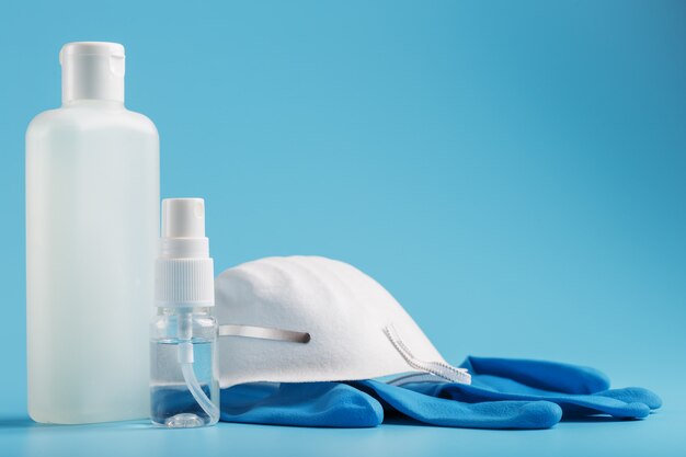 Stilleven van antivirusbescherming op een blauwe achtergrond, masker, rubberen handschoenen, een fles handdesinfecterend middel, antiseptische gel.