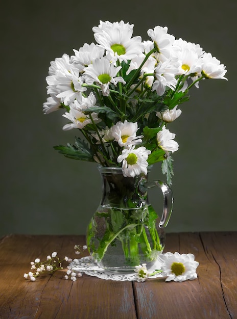 Stilleven van bloemen van witte kamilles in een glazen kan