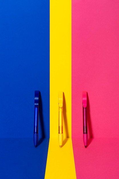 Foto stilleven van drie pennen in lijn op kleurrijke en geometrische achtergrond
