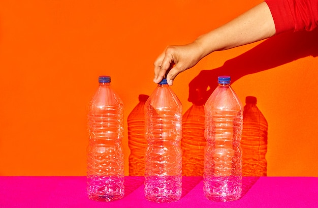 Stilleven van drie plastic flessen waarvan één hand er één vasthoudt. recycling, milieuconcept