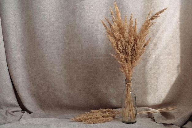 Stilleven van een boeket gedroogde bloemen in een glazen fles op een achtergrond van linnen stof