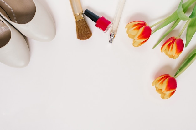 Stilleven van een fashionista. Cosmetische achtergrond voor vrouwen. Stijlvolle accessoires, een boeket tulpen en bloggerskleding. Een spatie kopiëren