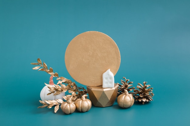 Stilleven van gouden en witte pompoenen, eikels en een huis op een turquoise achtergrond. Minimalistisch herfstconcept met kopieerruimte