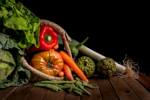 Foto stilleven van groenten uit de tuin op houten tafel en zwarte achtergrond