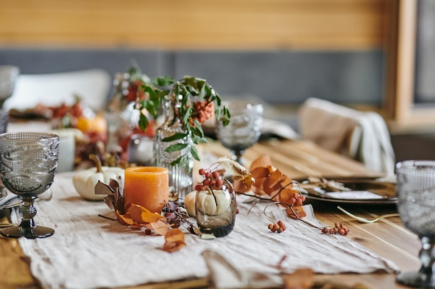 Stilleven van herfstbladeren in vaas en fles op geserveerd feestelijke tafel