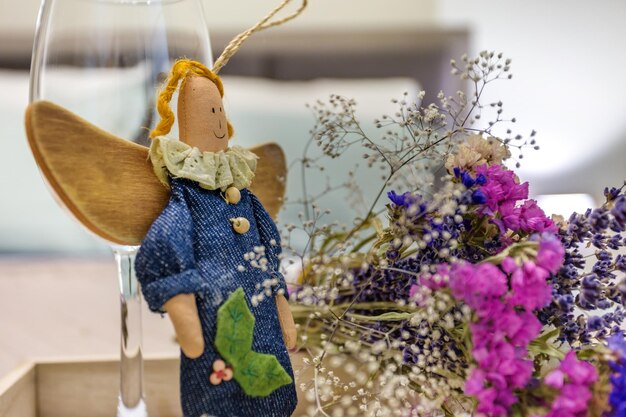 Stillevendecoratie van twee lege wijnglazen een zelfgemaakte lappen engel speelgoed en boeket droogbloemen