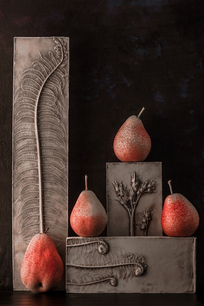 Foto stillevenvoedsel met groep van perenforel en oude gips botanische bas reliëfs op donker