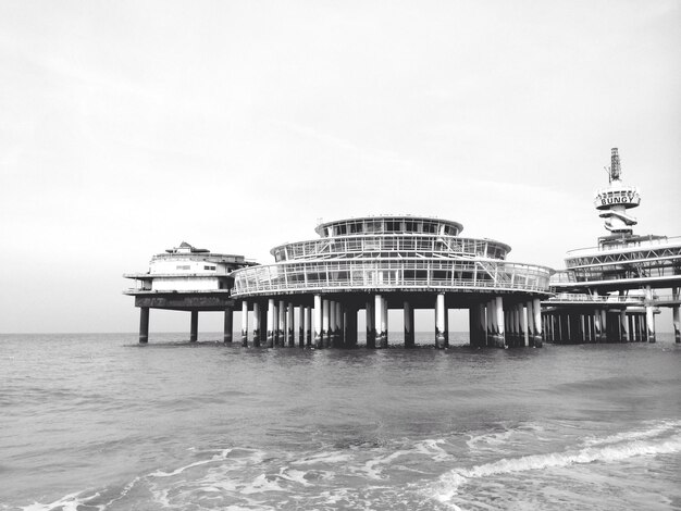 Stilt buildings in sea against clear sky