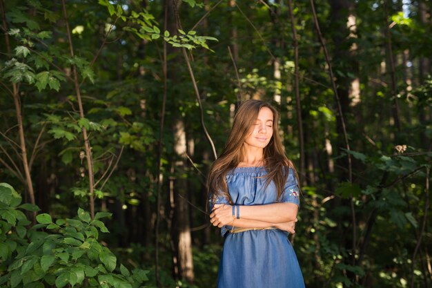 Stilte, natuur, mensen en zomer concept - Jonge vrouw genieten van het groene bos.