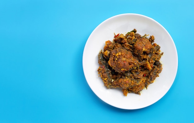 Stir fried catfish with curry paste on blue background.