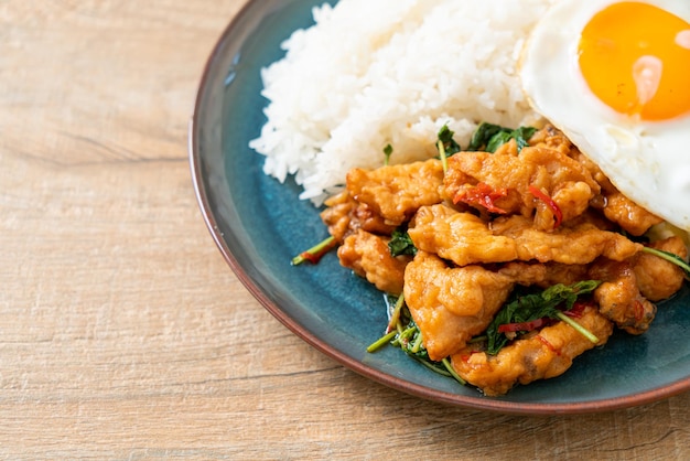 Stir-fried fried fish with basil and fried egg topped on rice -\
asian food style