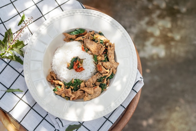 Stir-fried meat with chili and basil served with steamed rice on white dish