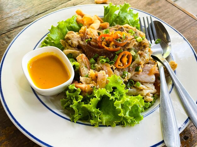 Stir fried noodle Thai Korat style with spoon and fork on plate at restaurant