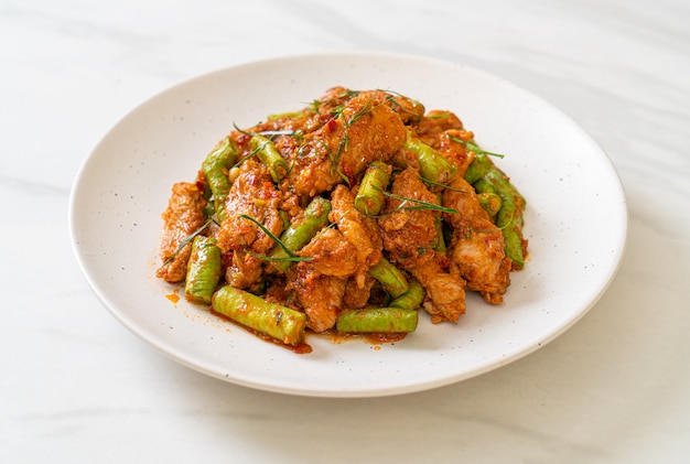 Mescolare il maiale fritto e la pasta di curry rosso con il fagiolo pungiglione