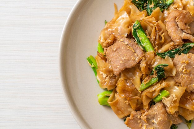 Spaghetti di riso saltati in padella con salsa di soia nera e maiale e cavolo nero, stile asiatico