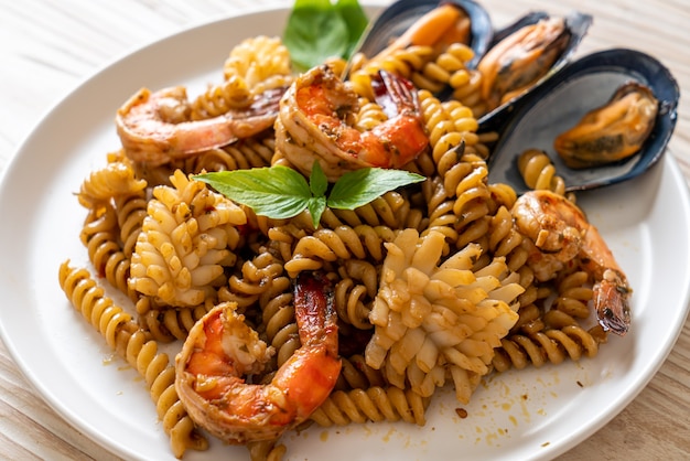 stir-fried spiral pasta with seafood and basil sauce. fusion food style