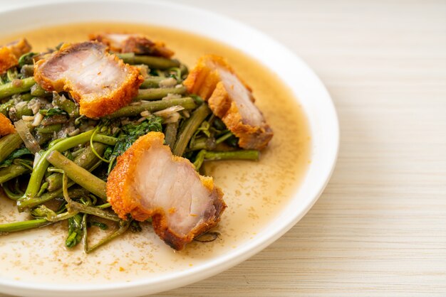 Stir-fried water mimosa with crispy pork belly on plate