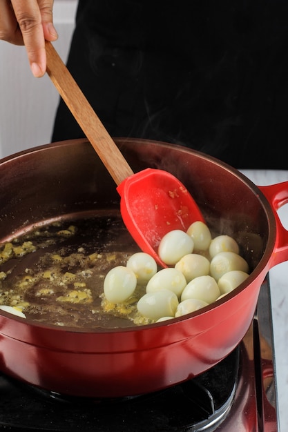 Stir Fry Boiled Quail Egg on Red Pan with Red Spatula. Cooking process in the Kitchen Making Quail Egg Manu/Korean Jangjorim