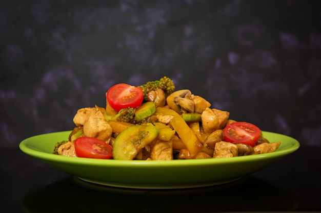 Stir fry chicken, zucchini and broccoli on dark