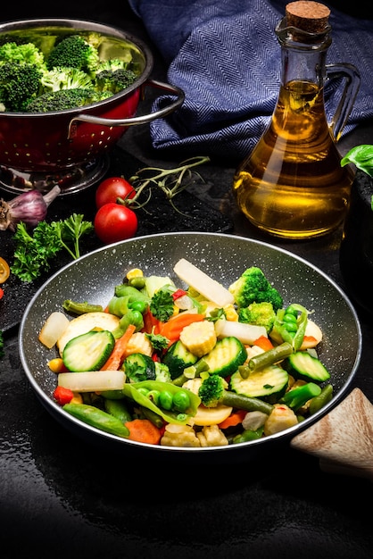 フライパンで新鮮な野菜を炒めるダークトーン黒のイメージ健康的な食事のアイデア