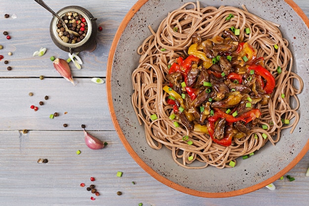 Stir fry from chicken hearts, paprika, onions and buckwheat noodles. Top view