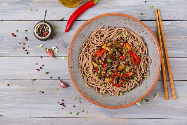 Stir fry from chicken hearts, paprika, onions and buckwheat noodles. 