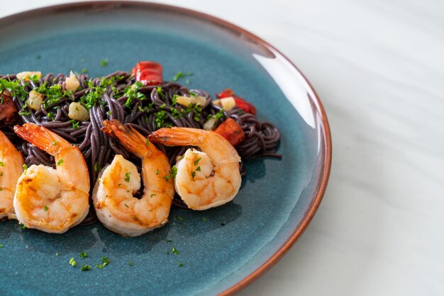 Photo stirfried black spaghetti with garlic and shrimps on plate