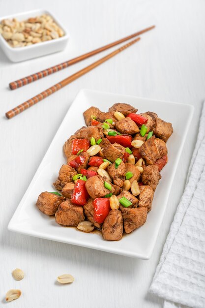 stirfried Chinese Kung Pao chicken with peanuts vegetables served on plate with chopsticks