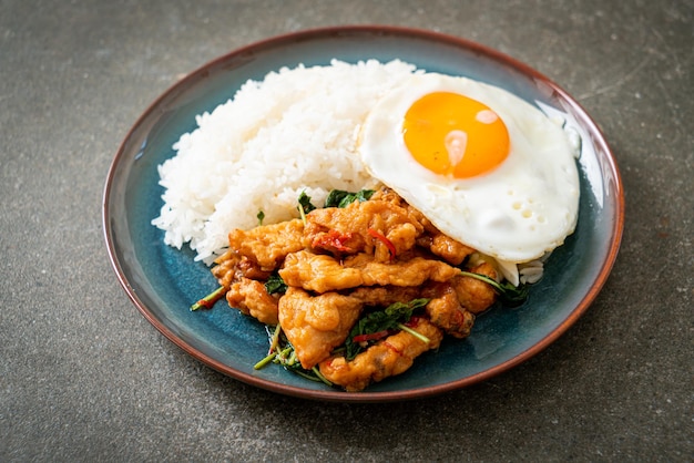 Stirfried fried fish with basil and fried egg topped on rice