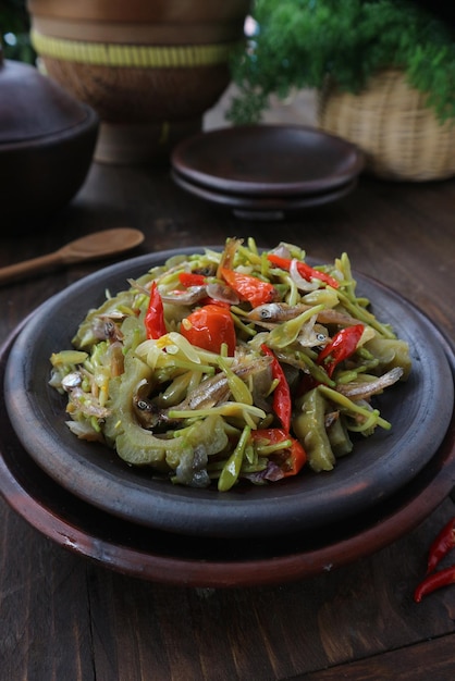 Foto fiori di papaya saltati in padella e pesce salato piccante indonesiano su un piatto