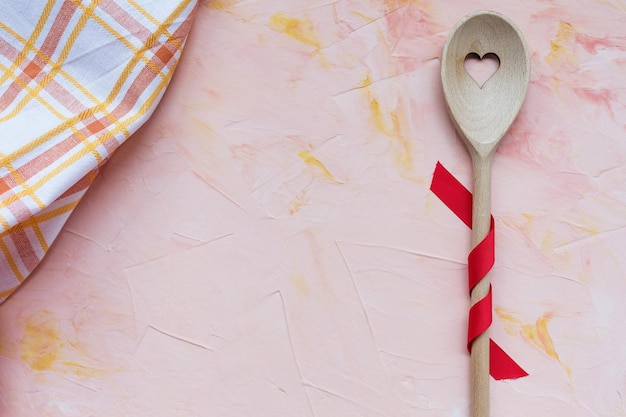 Stirring spoon and kitchen towel on a pink background