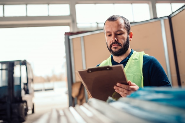 Photo stock clerk checking warehouse inventory in the warehouse factory