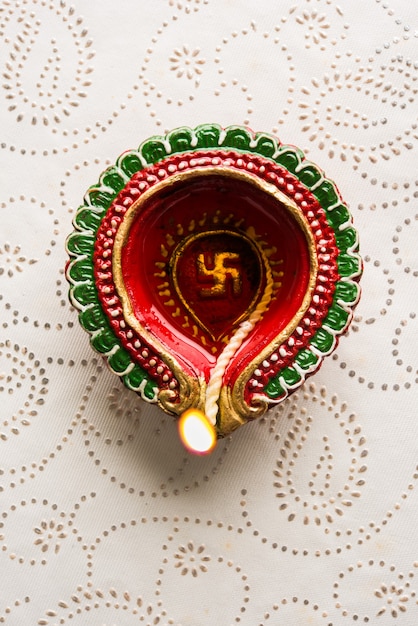 Stock photo of beautiful diwali diya with gifts and flowers, over decorative background, moody lighting and selective focus