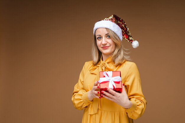 Stock photo of cheerful adult woman with short dyed hair wearing Christmas t-shirt, holding stack of beautiful wrapped Christmas gifts in hands and smiling