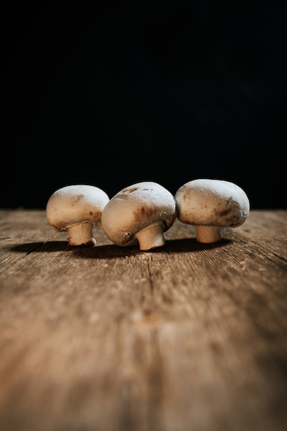 Stock photo of group of mushrooms on wooden table and black background.