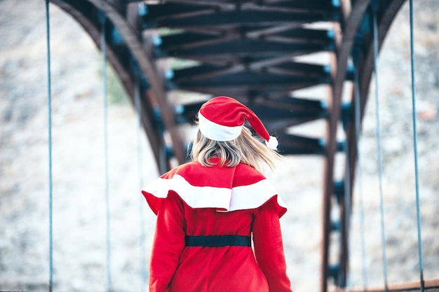 Stock photo of Mama Noel walking backwards on a wooden bridge with a red bag in her hand