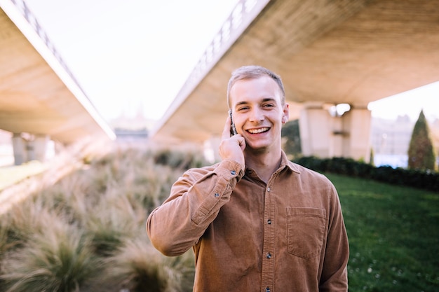 Stock photography of young boy talking on the phone and smiling in the middle of an office area.