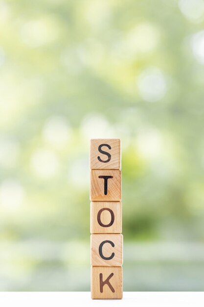 Stock word is written on wooden cubes on a green summer background Closeup of wooden elements