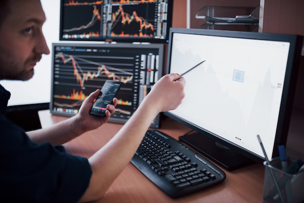 Stockbroker in shirt is working in a monitoring room with display screens. Stock Exchange Trading Forex Finance Graphic . Businessmen trading stocks online