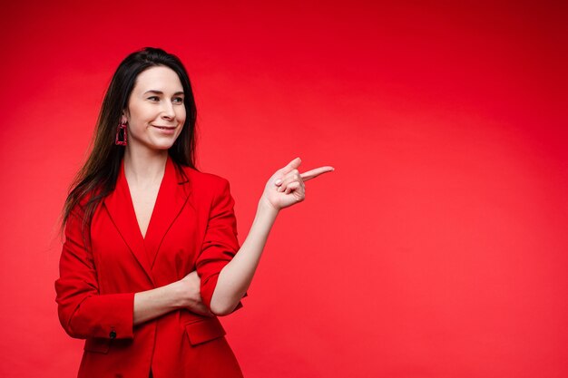 Stockfoto portret van een vrolijke lachende brunette in rode jas wijzend met wijsvinger