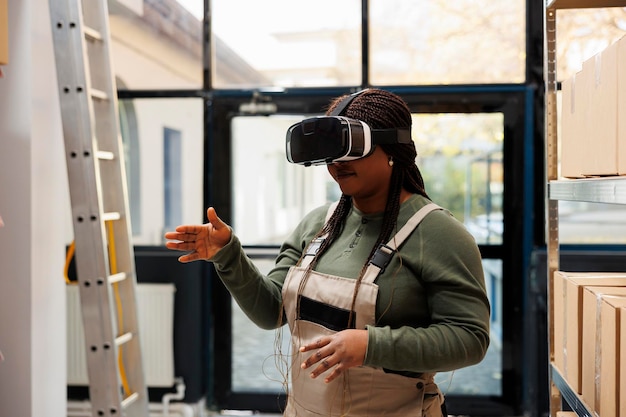 Stockroom supervisor enjoying using virtual reality goggles in warehouse, analyzing goods checklist. Storage room employee wearing industrial overall, preparing customers orders in storehouse