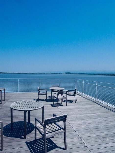 Foto stoelen bij het zwembad tegen de zee tegen de heldere blauwe lucht