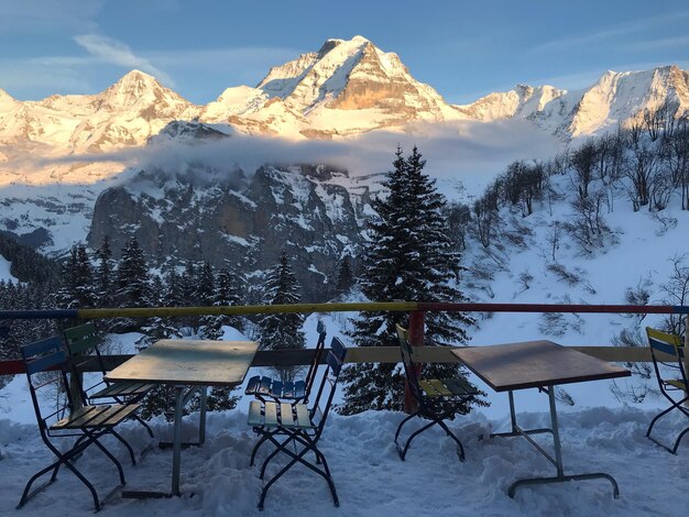 Foto stoelen en tafels tegenover besneeuwde bergen in de winter