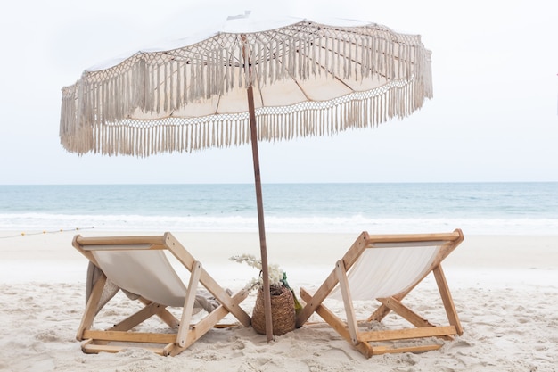 Stoelen met paraplu op wit zandstrand tegen de vakantieconcept van de zeegezichtzomer