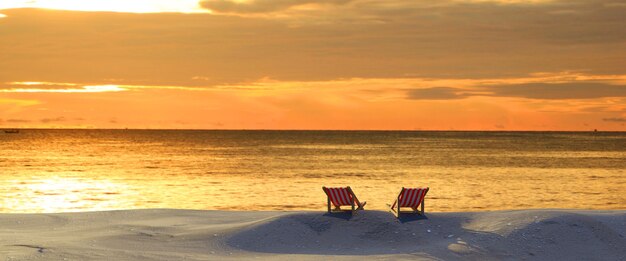 Stoelen op het strand bij zonsondergang