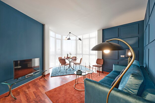 Foto stoer ingerichte woonkamer van een huis met blauwe muren, een groot halfrond raam en een blauw fluwelen bank